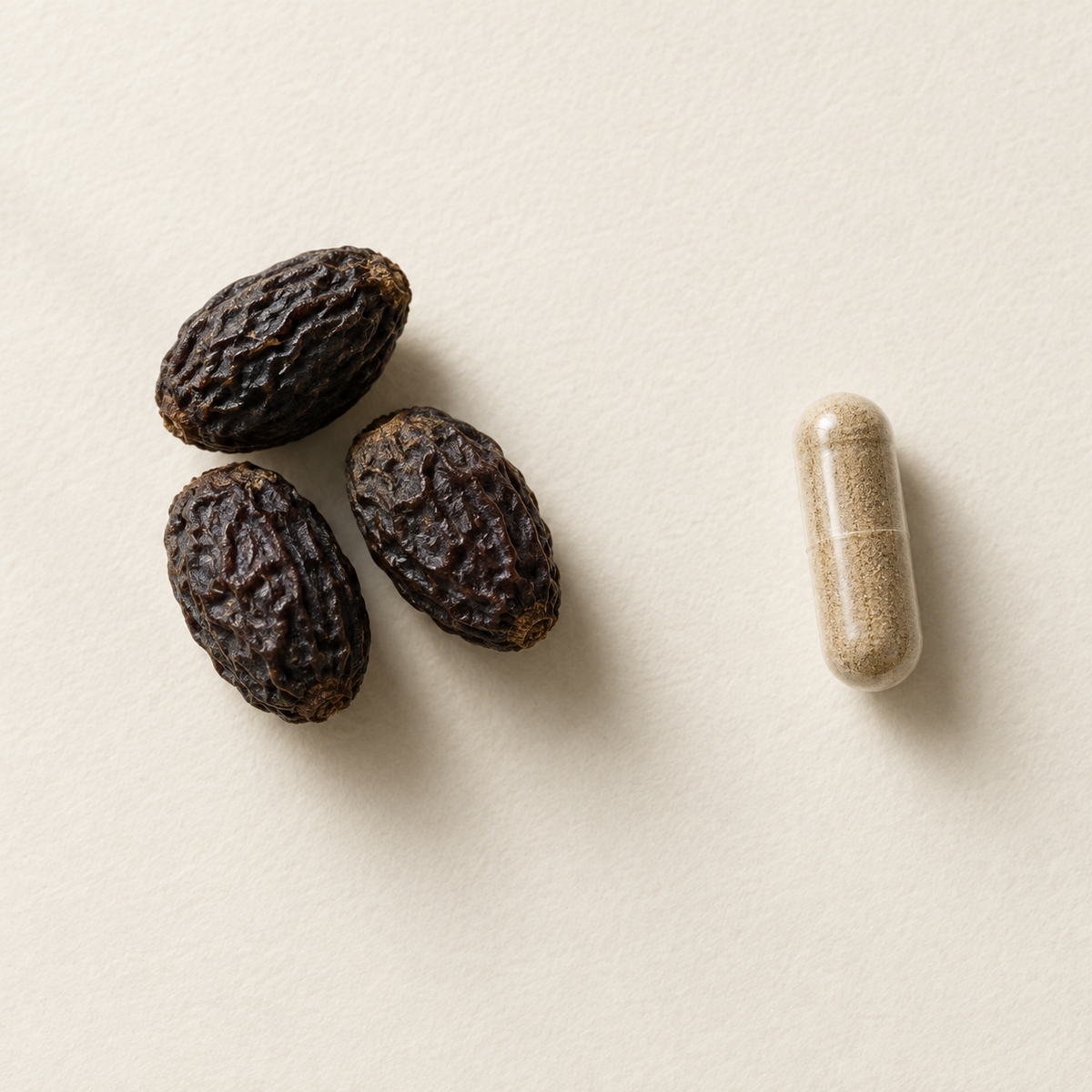Three dried saw palmetto berries beside one Complete Prostate Health capsule filled with tan extract powder